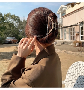 Outdoor shot of a model wearing a gold triangular metal hair claw clip with pearls