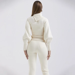 Rear view of beige two-piece knit set featuring hooded lantern sleeve top and pants