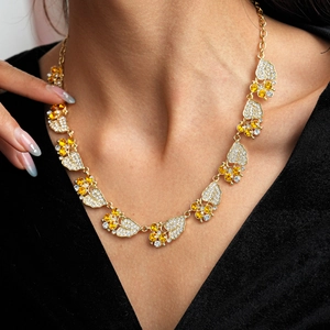 Detail van vintage dubbellaagse ketting met gouden bladeren en gele zirkoniasteentjes