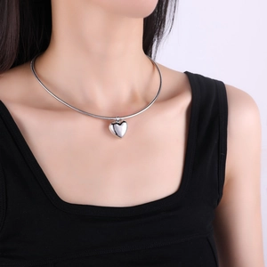 Polished silver heart pendant necklace on snake chain choker style worn by model