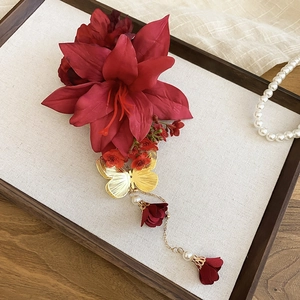 Détail d'une pince à cheveux fleur rouge avec papillon doré et pampilles de perles