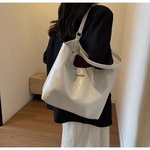 Rear view of a model wearing a large white PU leather tote bag with a metal buckle detail