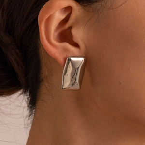 Polished silver stainless steel rectangular hoop earrings shown on a model's ear