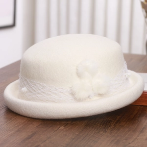 Detail of elegant cream wool dome hat with delicate mesh lace and three soft pom-poms