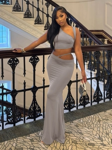 Detail of grey one-shoulder crop top and slim fit maxi skirt set on staircase