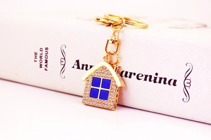 Close-up of golden house keychain with sparkling rhinestones and blue enamel window details