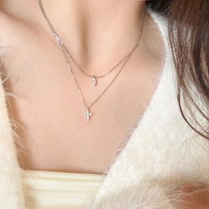 Close-up of a double-layered S925 silver necklace with cross and marquise drop pendants
