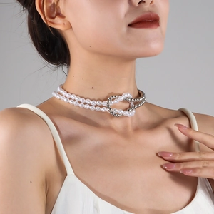 Detail of layered necklace featuring white pearls and silver beads with interlocking clasp