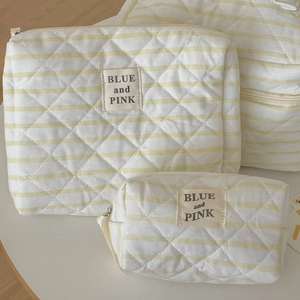 Dettaglio di trousse trapuntate a righe in tre dimensioni con texture morbida e zip