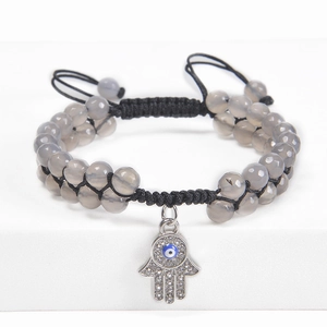 Detail of grey agate beaded bracelet with Hamsa Hand and Evil Eye charm on white stand