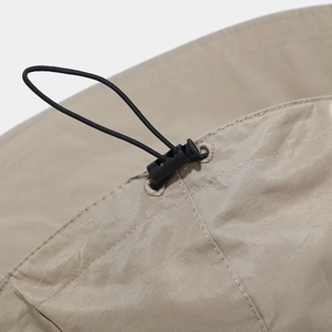 Detail of adjustable elastic drawstring and toggle on a khaki sun hat with ripstop fabric