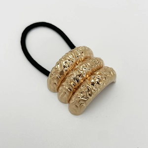 Close-up of golden hammered alloy u-shaped hair tie with black elastic band detail