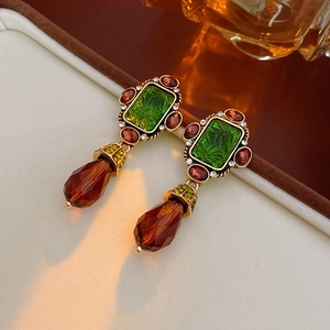 Macro detail of vintage emerald glass earrings with small diamonds and teardrop pendants