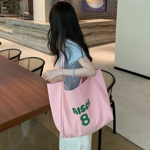 Lifestyle shot of large pink canvas tote bag with green print used in a cafe setting