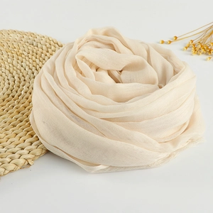 Elegant beige cotton linen scarf with frayed edges styled in a floral shape on white background