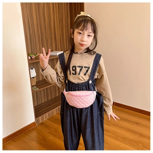 Toddler girl modeling a pink quilted waist bag with a casual long sleeve shirt and overalls