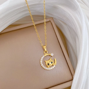 Close-up of gold moon and cat necklace pendant with blue eyes and micro-set crystals