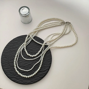 Elegant multi-layer white pearl necklace with glossy round beads on a black stone display