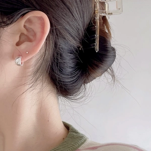 Close-up of minimalist silver geometric hoop earring worn by a model with a clear hair claw