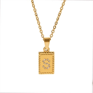 Macro detail of 18k gold plated square pendant with CZ stones and letter S on O-chain