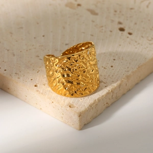 Adjustable gold hammered texture wide band ring displayed on a beige stone block