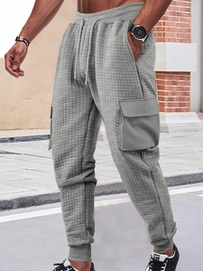 Detail of grey waffle knit cargo pants featuring side flap pockets and textured fabric