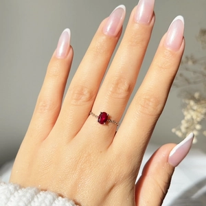 Macro shot of an adjustable chain ring with a red oval-cut zircon in silver setting