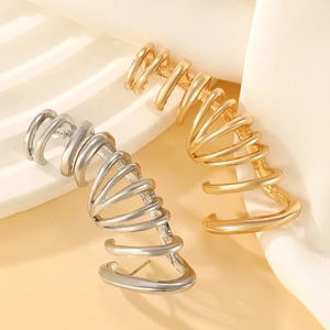 Detailed view of punk dragon ear cuffs in gold and silver plating on white silk