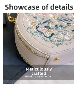Close-up of intricate floral embroidery and golden zipper on beige round leather handbag