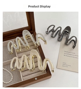 Detailed view of wave-shaped hair claws with rhinestones and pearls on wood tray
