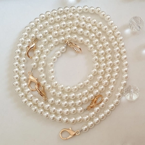 Macro shot of long cream pearl chain strap with elegant gold lobster clasps and smooth beads