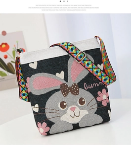 Detail of canvas crossbody bag featuring a bunny embroidery and colorful ethnic strap