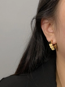 Close-up of golden layered disc earrings worn by a model for a stylish metal look