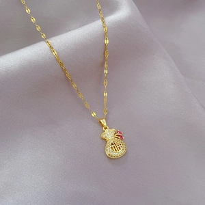 Detail of gold titanium steel money bag pendant with crystals on silk fabric