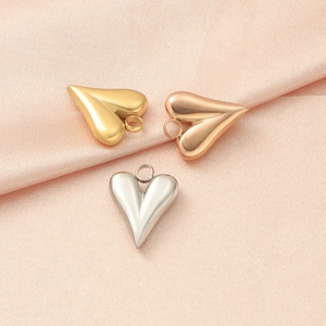 Three heart pendants in gold, rose gold, and silver on soft pink silk background