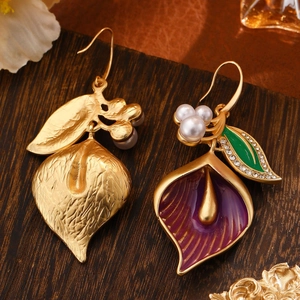 Macro view of calla lily earrings with purple enamel, pearls, and vintage gold finish
