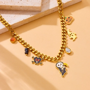 Close-up of golden Halloween necklace with pumpkin, ghost, and skull charms on stone