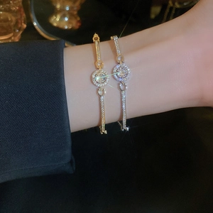 Minimalist gold and silver bracelets with colorful zircons worn on a wrist for women