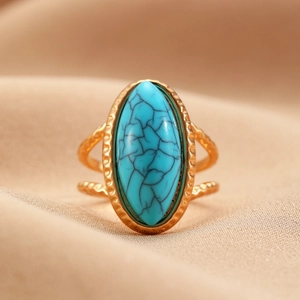 Detalle de anillo dorado vintage con piedra turquesa ovalada y diseño de doble banda