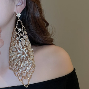 Close-up of sparkling rhinestone drop earrings worn on a model with golden metal base