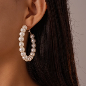 Close-up of elegant large white faux pearl hoop earrings worn by a model for a classy look