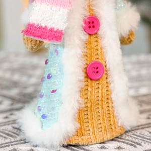 Detail of knitted gingerbread doll with pink sequins, soft faux fur, and plastic buttons