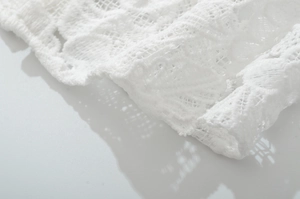 Macro detail of white delicate lace fabric with intricate floral embroidery patterns