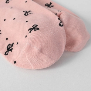 Close-up of pink cotton socks featuring black polka dots and a delicate bow detail