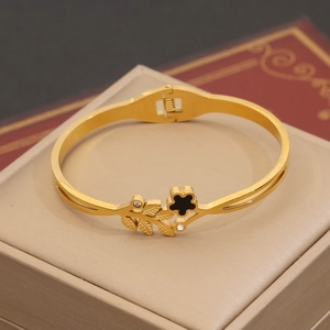 Détail d'un jonc doré à fleurs et zircons posé sur une boîte à bijoux beige