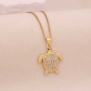 Macro detail of gold turtle pendant with clear square zircon stones on a gold chain