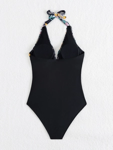 Detail view of black one-piece swimsuit featuring tropical floral ties on a white background