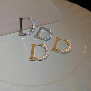 Détail de boucles d'oreilles en forme de D avec zircons sur plateau céramique