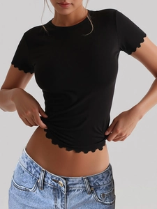 Detail of black crop top with ruffled wave edges and elastic slim fit fabric on model