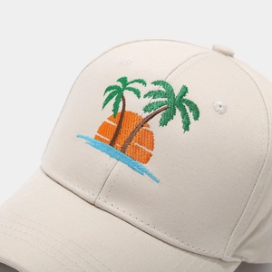 Gros plan de la broderie palmier et coucher de soleil sur une casquette en coton beige